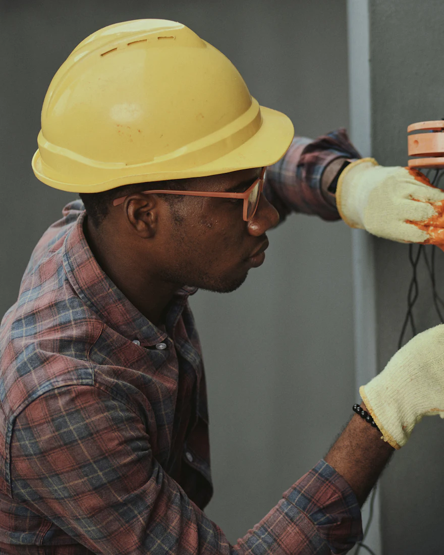 Electrician in a safety helmet working on an electrical panel